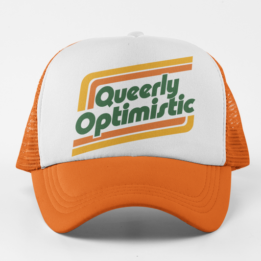 A white and orange trucker hat with a retro-style graphic on the front panel that reads 'Queerly Optimistic' in green text with orange and yellow stripes, set against a plain white background.