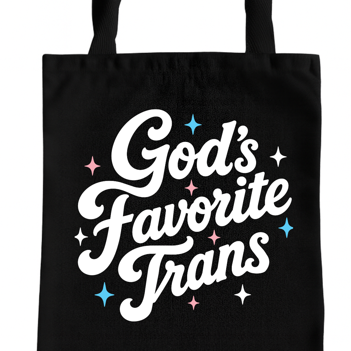 A black canvas tote bag with the phrase 'God's Favorite Trans' printed in white script, accented with small pink, blue, and white star graphics, shown against a plain white background.