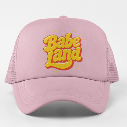 A light pink trucker hat with a yellow and orange 3D-style 'Babe Land' logo on the front, set against a plain white background.